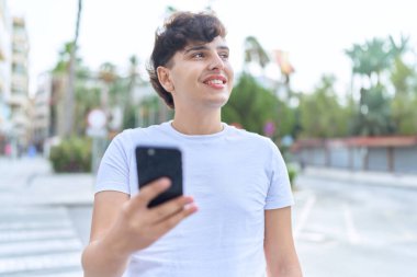 Non binary man smiling confident using smartphone at street