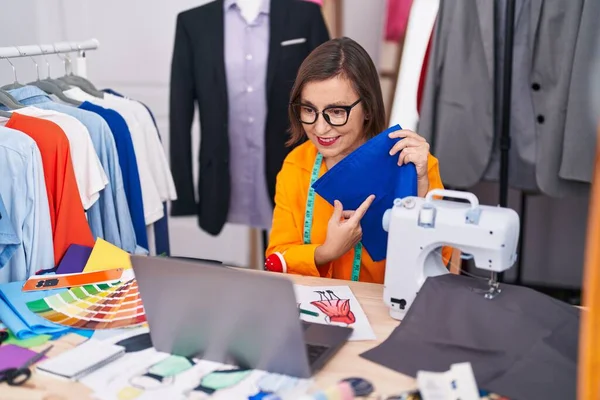 中年妇女裁缝在裁缝店用笔记本电脑拿着布 — 图库照片