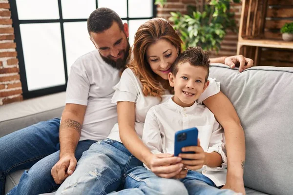Familia Usando Teléfono Inteligente Abrazándose Uno Otro Sentado Sofá Casa — Foto de Stock