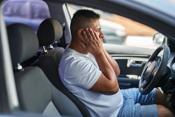 Young latin man stressed driving car at street