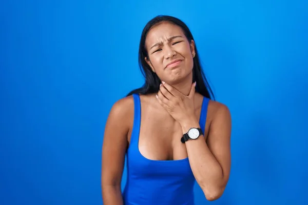 Hispanic Woman Standing Blue Background Touching Painful Neck Sore Throat — стокове фото