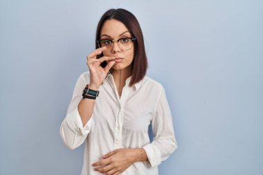 Young hispanic woman standing over white background mouth and lips shut as zip with fingers. secret and silent, taboo talking 