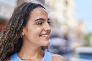 Young beautiful hispanic woman smiling confident looking to the side at street