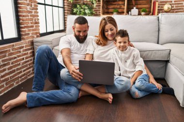 Family watching movie hugging each other sitting on floor at home