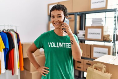 Gönüllü üniformalı genç İspanyol kadın yardım merkezindeki akıllı telefondan konuşuyor.