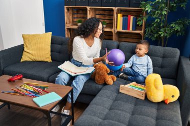 Mother and son sitting on sofa playing at home