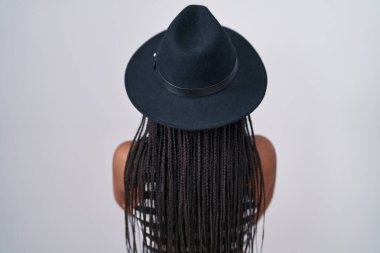 Saçları örgülü, şapka takan ve güneş gözlüklü genç Afro-Amerikalı arkasını dönüp kollarını kavuşturmuş ona bakıyordu. 