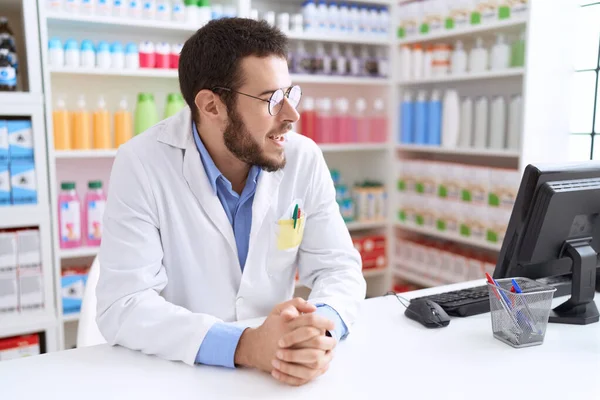 Joven Farmacéutico Hispano Sonriendo Confiado Sentado Mesa Farmacia —  Fotos de Stock