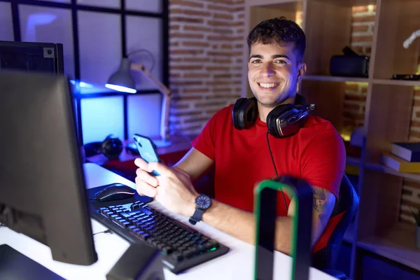 stock image Young hispanic man streamer using computer and smartphone at gaming room