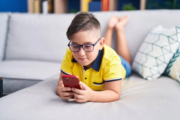 Evdeki Kanepede Uzanmış Akıllı Telefon Kullanan Sevimli Spanyol Çocuk — Stok fotoğraf