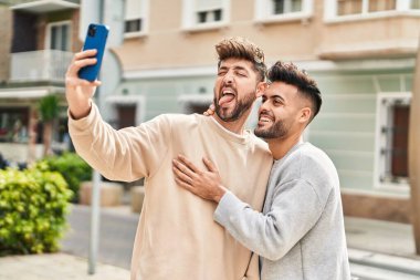 Young couple hugging each other making selfie by the smartphone at street