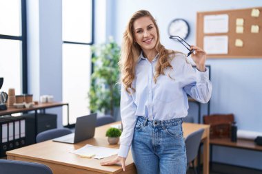 Genç sarışın iş kadını ofiste kendine güvenen gülümseyen