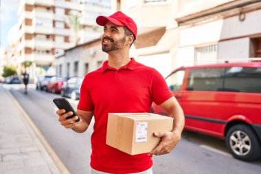 Genç İspanyol kurye sokakta akıllı telefon paketi kullanıyor.