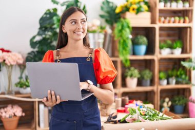 Çiçekçiye dizüstü bilgisayar kullanarak gülümseyen güzel İspanyol kadın.