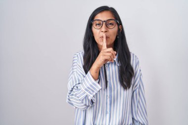 Gözlüklü genç İspanyol kadın parmakları dudaklarında sessiz olmak istiyor. sessizlik ve gizli konsept. 