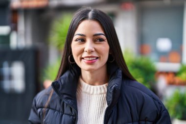 Young beautiful hispanic woman smiling confident looking to the side at street