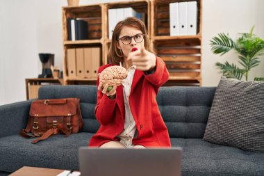 Muayenehanedeki genç esmer kadın elinde beyni kamerayı işaret ederek sana ve kendine güveni tam bir jest yapıyor. 