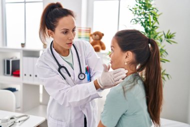 Kadın, kız, doktor ve hasta klinikte boğazlarını inceliyor.