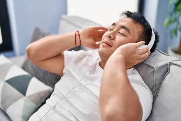 Young Chinese Man Listening Music Sitting Sofa Home — Φωτογραφία Αρχείου