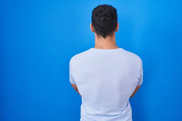 Junger Hispanischer Mann Steht Vor Blauem Hintergrund Und Blickt Rückwärts — Stockfoto