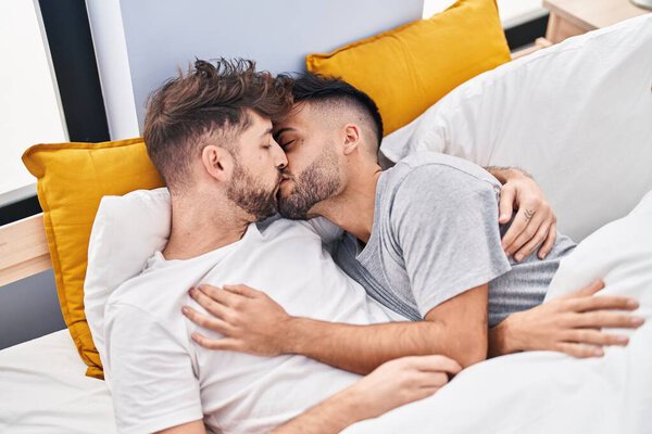 Young couple hugging each other and kissing lying on bed at bedrooom