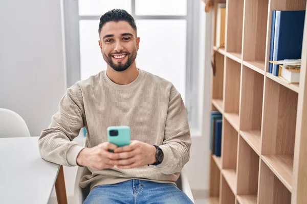 年轻的阿拉伯男子在家里用智能手机自信地微笑 — 图库照片