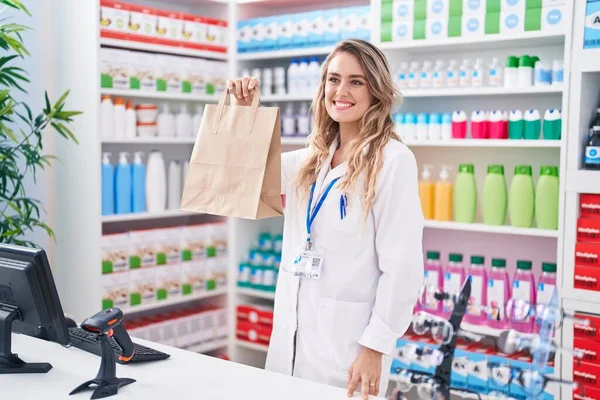 Young Blonde Woman Pharmacist Smiling Confident Holding Shopping Bag Pharmacy — Foto Stock