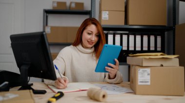 Genç kızıl saçlı kadın, iş kadını. Ofiste dokunmatik ped kullanıyor.