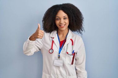 Genç Afro-Amerikan kadın doktor üniforması giyiyor ve steteskop elinde mutlu parmaklar hareketi yapıyor. Kameraya bakıp başarıyı gösteren ifade. 