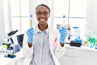 Laboratuvarda test tüpleri tutan Afrikalı Amerikalı kadın bilim adamı.