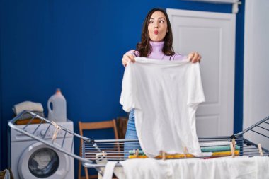 Genç esmer kadın çamaşır ipine kıyafet asıyor. Ağzı ve şaşı gözleriyle balık yüzü yapıyor. Deli ve komik.. 