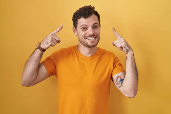 Young Hispanic Man Standing Yellow Background Smiling Pointing Head Both — Stock Photo, Image