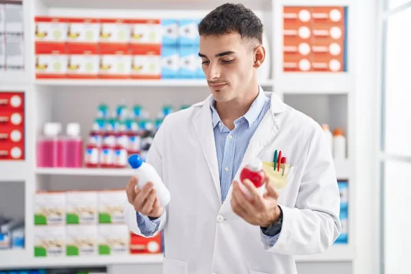 Jovem Homem Hispânico Farmacêutico Sorrindo Confiante Segurando Garrafas Medicação Farmácia — Fotografia de Stock
