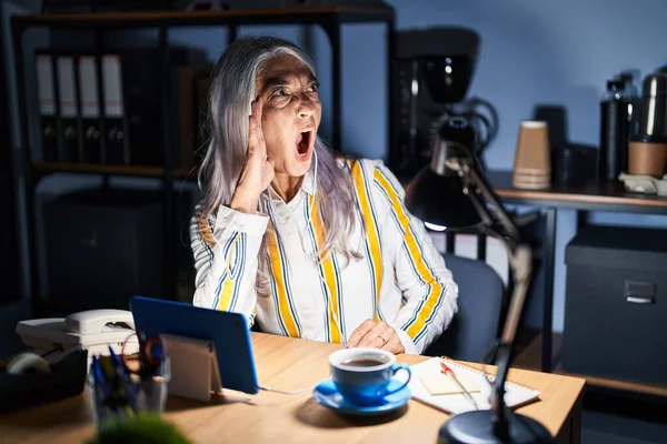 深夜のオフィスで働く白髪の中年女性は大声で叫び 口の中で手をつないで大声で叫ぶ コミュニケーションの概念 — ストック写真