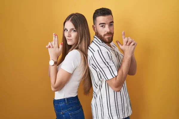 Young Couple Standing Yellow Background Holding Symbolic Gun Hand Gesture — Stock Photo, Image