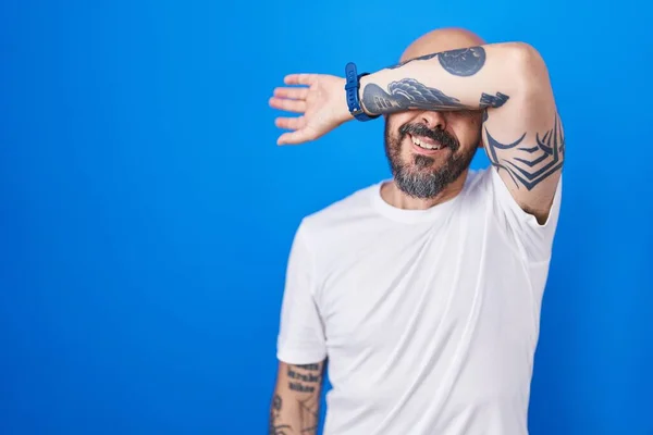 Hispanic Man Tattoos Standing Blue Background Covering Eyes Arm Looking — Stock Photo, Image