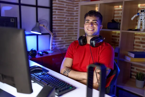 stock image Young hispanic man streamer smiling confident sitting with arms crossed gesture at gaming room
