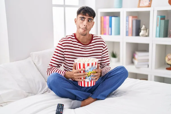 Junger Hispanischer Mann Der Popcorn Isst Sitzt Auf Dem Bett — Stockfoto