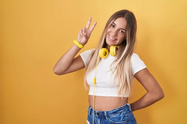 Mujer Rubia Joven Pie Sobre Fondo Amarillo Con Auriculares Sonriendo — Foto de Stock
