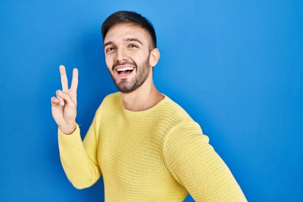 Hispanic Man Standing Blue Background Smiling Looking Camera Showing Fingers — Stok fotoğraf