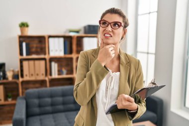 Muayenehanede çalışan genç bir kadın bir soru hakkında endişeli ve gergin bir şekilde düşünüyor. 