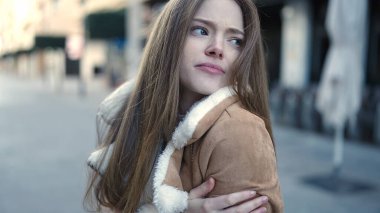 Young blonde woman standing by christmas tree doing heart gesture with hands at street