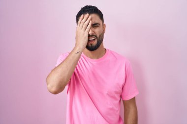 İspanyol genç adam pembe arka planda duruyor. Yarı yüz, göz ve ağız kaplamasından yoruluyor. Yüzüm acıyor.. 