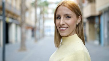 Sokakta kendine güvenen genç sarışın kadın gülümsüyor