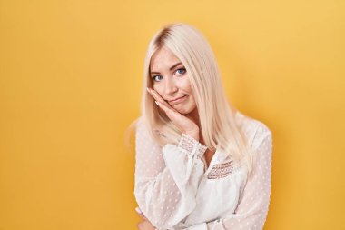 Caucasian woman standing over yellow background thinking looking tired and bored with depression problems with crossed arms. 