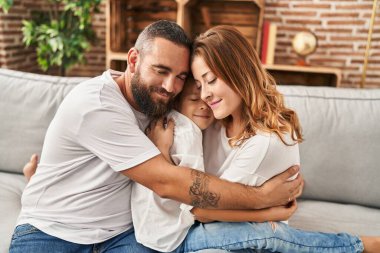 Family hugging each other sitting on sofa at home