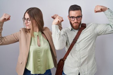 Beyaz arka planda duran genç çift gururla gülümseyen kol kaslarını gösteriyor. fitness konsepti. 