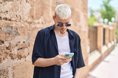 Sokakta akıllı telefon kullanan beyaz bir genç.