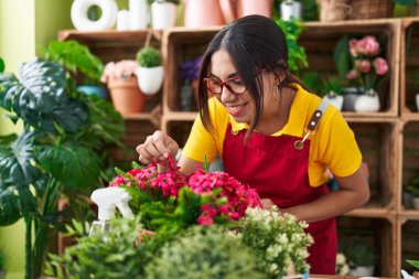 Young beautiful arab woman florist smiling confident touching flower at flower shop
