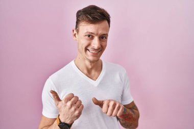 Pembe arka planda duran beyaz bir adam arka tarafı işaret ediyor. Elleri havada, kendinden emin bir şekilde gülümsüyor. 